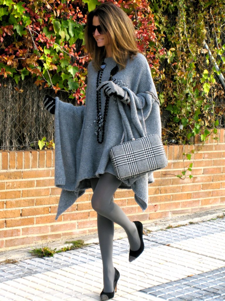 Девушка в пончо серого цвета, с серой сумкой в руке и серых колготках