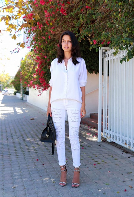 Модель в белых джинсах и блузке, черная сумка и босоножки