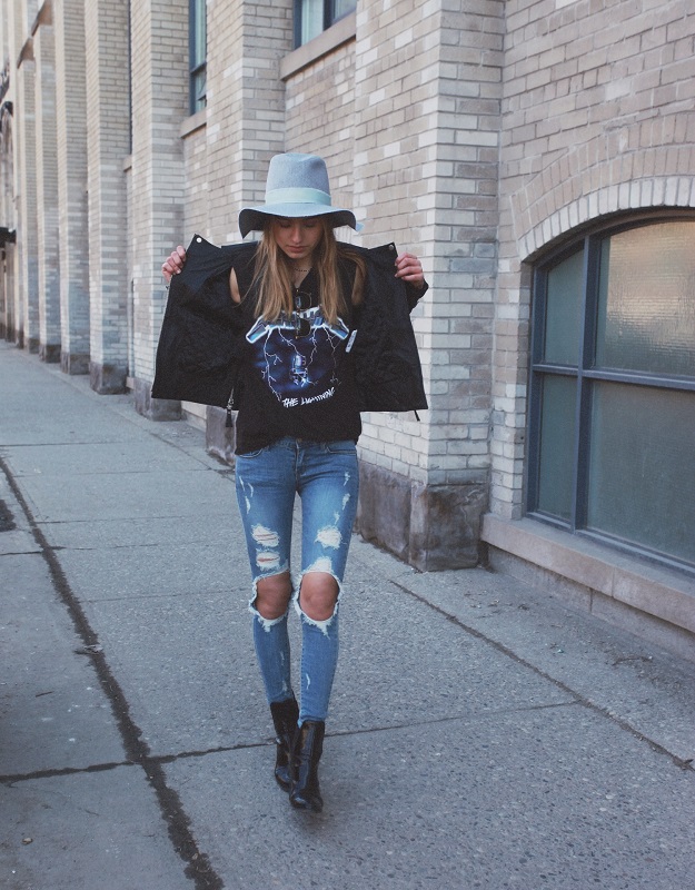 Девушка в рваных джинсах, черных ботильонах, футболке и шляпе