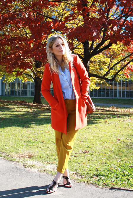 Модель в бриджах горчичного цвета, рубашка и оранжевое пальто