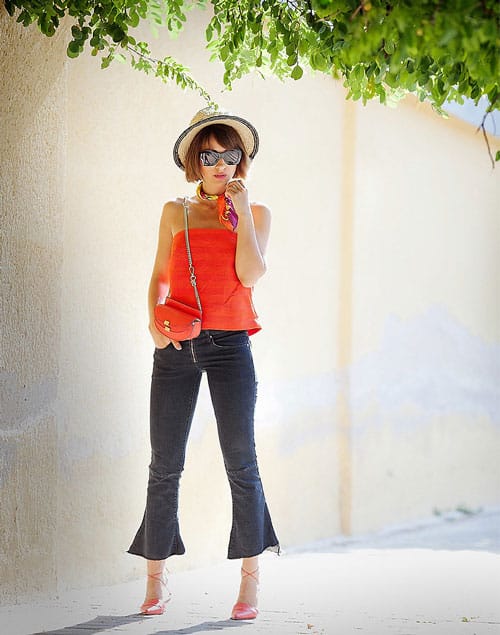 Девушка в укороченных серых джинсах клеш и оранжевый топ