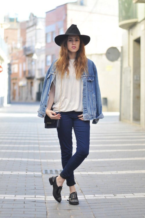 Девушка в темных джинсах, светлой джинсовке и черной шляпе